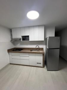 a kitchen with white cabinets and a stainless steel refrigerator at Lindo departamento en Punta Hermosa in Punta Hermosa