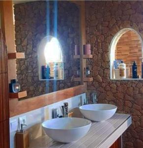 a bathroom with two sinks and a stone wall at OROKA EDEN in Ambondrona