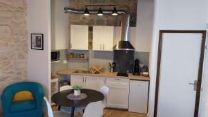 une cuisine avec une table et une chaise bleue dans l'établissement Logement 3 Apparts Centre historique St Gilles MaisoncarreeConciergerie, à Saint-Gilles