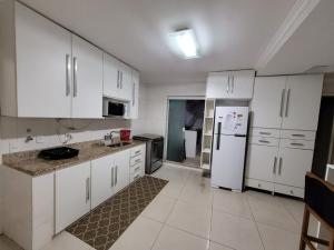 cocina con armarios blancos y nevera blanca en Apartamento Copacabana Frente Mar, en Río de Janeiro
