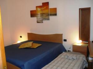a bedroom with a blue bed and two paintings on the wall at Casa di Tony in Trapani