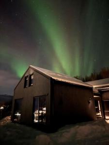 a house with the aurora in the sky behind it at Nybygget arkitekt tegnet Snøhetta i vakker natur in Sand