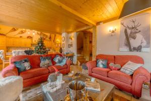 una sala de estar con sofás rojos y un árbol de Navidad en superbe chalet Amitie jacuzzi proche lac et du centre avec reduction multipass ete, en Les Gets