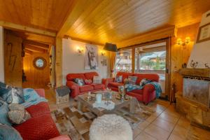 una sala de estar con sofás rojos y una mesa. en 70m des pistes de ski, Superbe CHALET avec jacuzzi et 3 stationnements gratuits en Les Gets