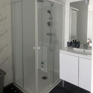 uma casa de banho branca com um chuveiro e um lavatório. em Room in Guest room - Home - Chambre independante a 10min Rer C et de Dourdan em Sermaise