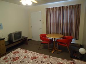 a hotel room with a table and chairs and a television at Hôtel-Motel Le Pharillon in Cap-des-Rosiers