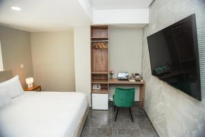 a bedroom with a bed and a desk with a television at Bahía Boutique House in Cartagena de Indias