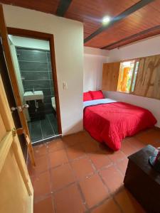 sypialnia z czerwonym łóżkiem i umywalką w obiekcie CABAÑA LOS NOGALES w mieście San Agustín