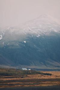 a snow covered mountain with a house in front of it at Glacier World - Hoffell Guesthouse in Hoffell