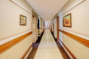 un pasillo con suelo de madera y pinturas en las paredes en Capital O Hotel Surabhi Elite Near Miraj Cinemas - Shalini Shivani en Surūrnagar