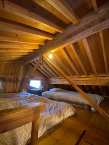 an attic room with two beds and a tv at 美瑛の静かな森の中のキャンプ場とログハウス。非日常体験、本当の自分を見つけ、自分らしく楽しく生きよう in Biei