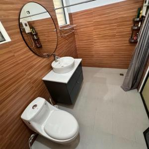 a bathroom with a toilet and a sink and a mirror at The Orchard Private Villa with Pool and Wifi in Cuenca Batangas in Cuenca