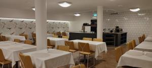 uma sala de jantar com mesas brancas e cadeiras amarelas em Hotel Esplanad em Mariehamn