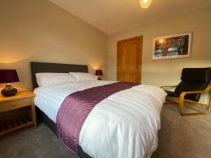 um quarto com uma cama grande e uma cadeira em Lyngarrie em Dufftown