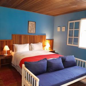 ein Schlafzimmer mit einem großen Bett mit blauer Wand in der Unterkunft Pousada Olho D'Água in Visconde De Maua