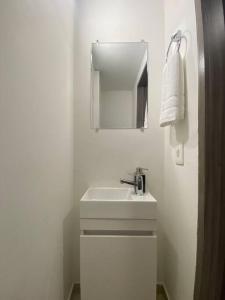ein weißes Badezimmer mit einem Waschbecken und einem Spiegel in der Unterkunft Espectacular e Increíble Apto Zona T, Chico in Bogotá