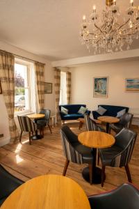 a restaurant with tables and chairs and a chandelier at Alexandra Hotel in Weymouth