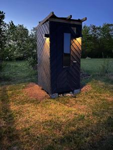 una casa negra sentada en el césped en Tiny summerhouse in Matsalu 