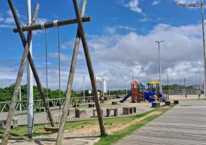 um parque infantil com baloiços e um calçadão de madeira em Casa a 200 mts da praia - prox Aeroporto NVG - CASA DA MEIA PRAIA em Navegantes