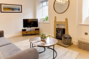 a living room with a couch and a tv and a table at Beam End Snainton - Modern 2-bedroom Stone Cottage in Snainton