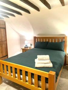 een slaapkamer met een houten bed en een groene deken bij Gardeners Cottage near the Norfolk Coast in Knapton