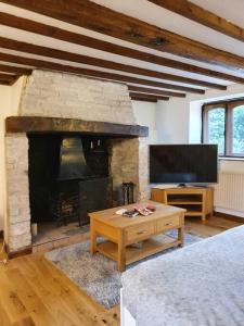 a living room with a fireplace and a flat screen tv at Gardeners Cottage near the Norfolk Coast in Knapton