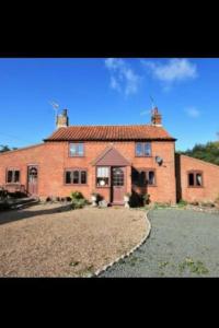 a large red brick house with a large yard at Gardeners Cottage near the Norfolk Coast in Knapton