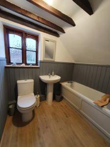 y baño con aseo, lavabo y bañera. en Gardeners Cottage near the Norfolk Coast, en Knapton