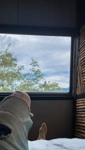 a person laying in bed looking out of a window at Cabaña 25km de Medellín, Benevento Glamping in Girardota