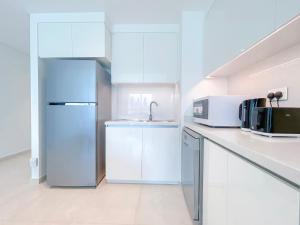 a white kitchen with a refrigerator and a sink at Stunning 2Bedroom with balcony Dubai Mall access in Dubai
