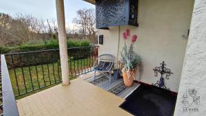 een veranda met een stoel, een plant en een hek bij La dame aux fleurs in Lavaur