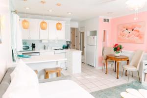 a kitchen with pink walls and a table and chairs at Palm Peach Tybee - Balcony - Oceanview "It's like, really pretty!" in Tybee Island