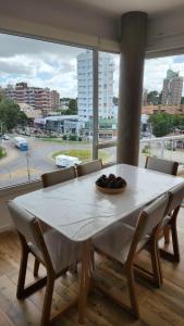 a dining room table with chairs and a large window at Departamento Pinamar Centro Status Tower in Pinamar