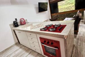 cocina con fogones rojos y encimera en Loft Alto Nível Teresópolis, en Teresópolis