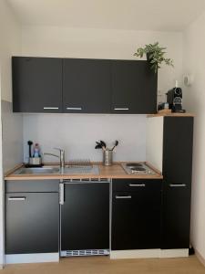 a kitchen with black cabinets and a sink at Ferienwohnung Panorama Schwarzwald in Herrischried