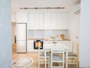 eine Küche mit weißen Schränken sowie einem weißen Tisch und Stühlen in der Unterkunft Premium Apartment in the Center in Tirana