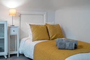 a bedroom with a bed with yellow pillows at Cosy 4th Floor studio apartment in Brick Lane in London