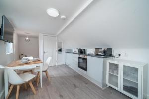 a kitchen with white cabinets and a table and chairs at Cosy 4th Floor studio apartment in Brick Lane in London
