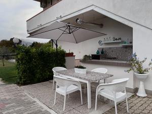 un patio con mesa, sillas y sombrilla en Parco delle Rose, en Sulmona