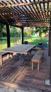 una mesa de picnic y bancos en una terraza de madera en QuintaLasBoleadoras en General Rodríguez