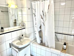 ein Badezimmer mit einem Waschbecken, einer Badewanne und einem Spiegel in der Unterkunft Panorama Domizil Ravensburg mit Alpenblick Balkon in Ravensburg