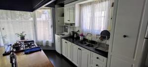cocina con armarios blancos y encimera negra en Casa en Chacras en Luján de Cuyo