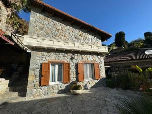 una casa in pietra con porte marroni e un portico di La Maison de Luisa a Bordighera