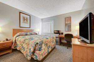 Habitación de hotel con cama, escritorio y TV. en Bridger Inn Hotel Downtown en Las Vegas