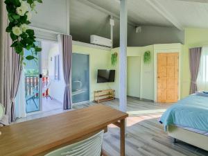 a bedroom with a bed and a table and a tv at Tina's Living Paradise II - Guesthouses with private pool, 5 min to beach in Rayong