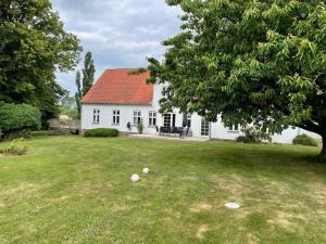 a white house with a yard with two balls on the grass at Havlykkegaard - en unik gammel dame ved Østersøen in Idestrup