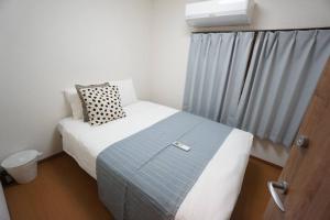 um pequeno quarto com uma cama e uma janela em Family Home Shimanouchi House Ⅱ em Osaka