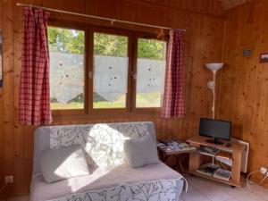 a living room with a couch and a desk with a television at Gites Les Rainettes in Vienne-en-Bessin