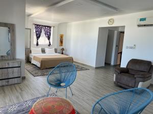 ein Schlafzimmer mit einem Bett, zwei Stühlen und einem Sofa in der Unterkunft Mjanaheri Beach Villas in Bwejuu