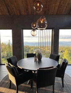 uma sala de jantar com mesa, cadeiras e janelas em Norefjell Chalet em Surteberg